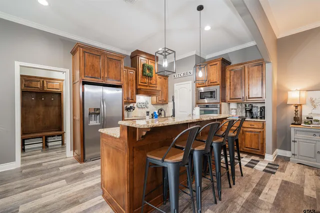 a kitchen with stainless steel appliances kitchen island granite countertop a table chairs and a refrigerator