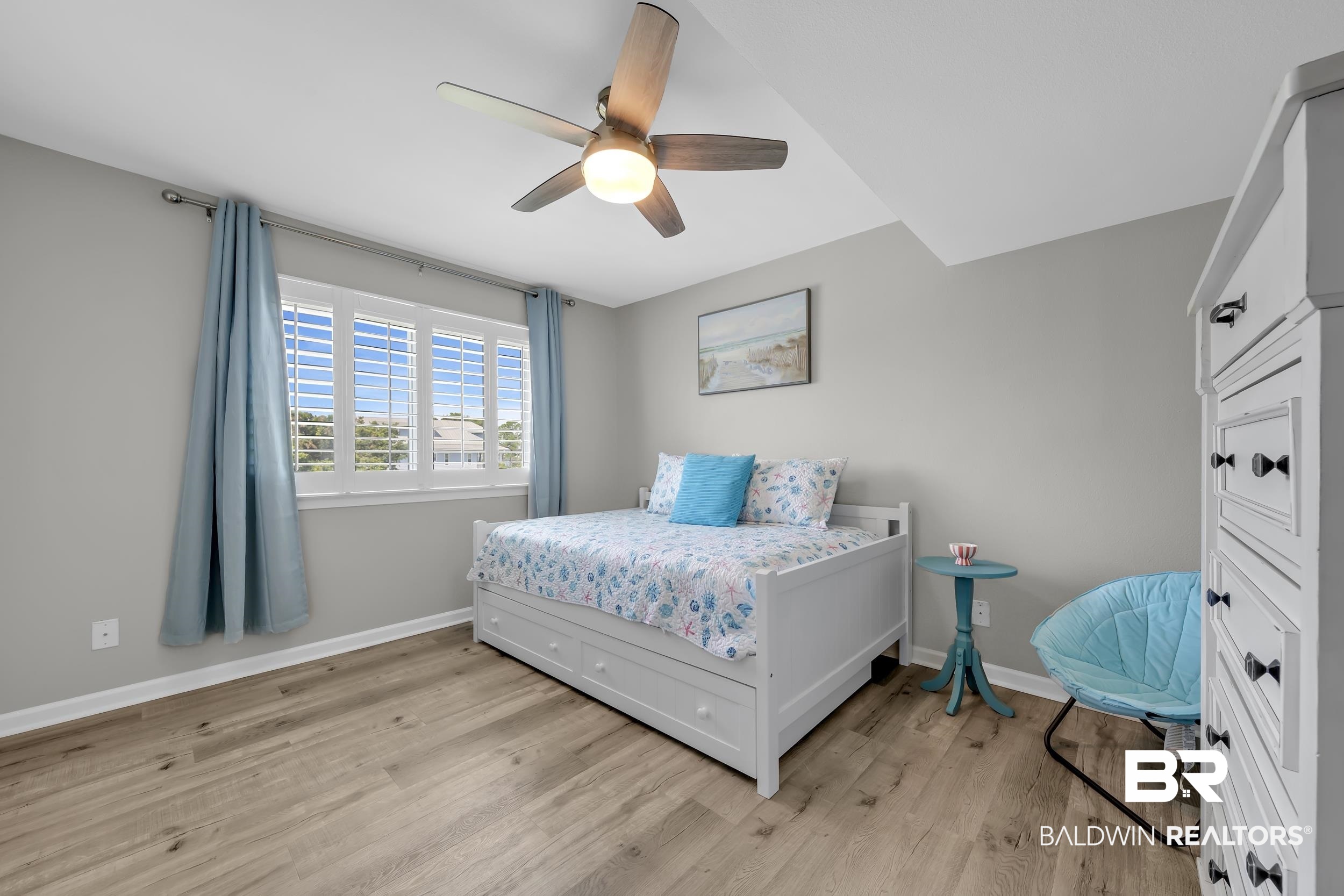 14100 River Road, Unit 211 Pensacola, FL 32507 - Photo 33 of 56 Well-lit room featuring wood-finish flooring, a ceiling fan with integrated lighting, and a window with plantation shutters