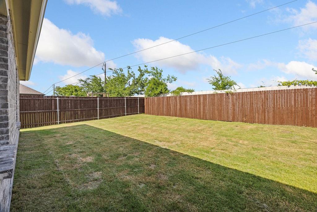 822 Ramble Road Lavon, TX 75166 - Photo 33 of 35 Expansive backyard featuring a manicured lawn, a full wood privacy fence, and a brick exterior wall