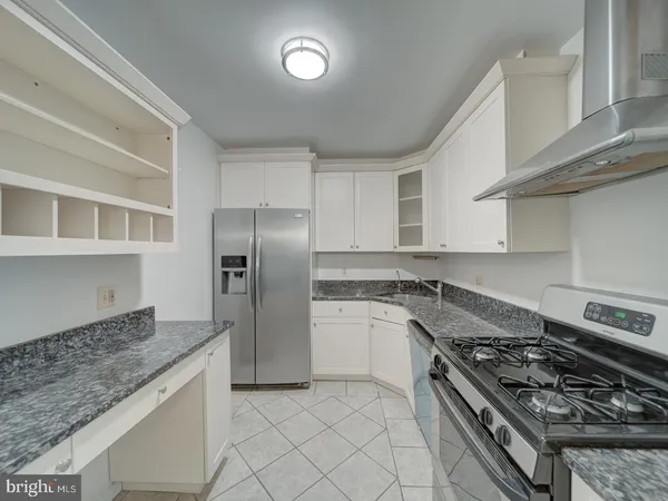 a kitchen with granite countertop white cabinets and a stove top oven