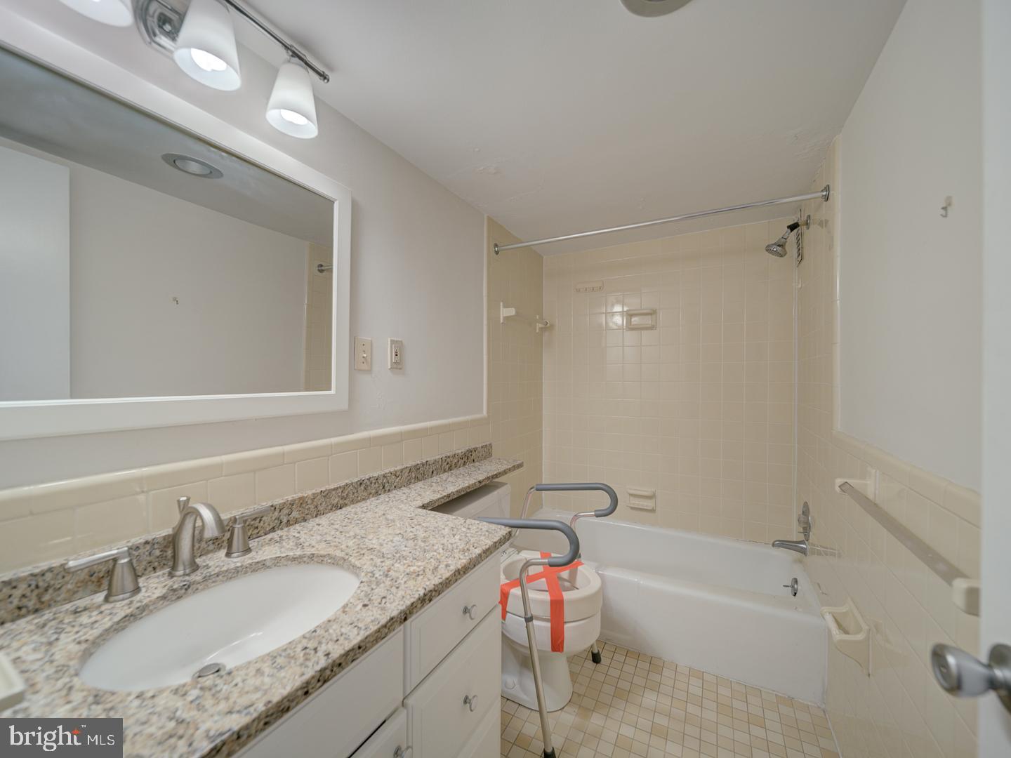 5101 River Road, Unit 411 Bethesda, MD 20816 - Photo 20 of 26 a bathroom with a granite countertop sink mirror bathtub and toilet