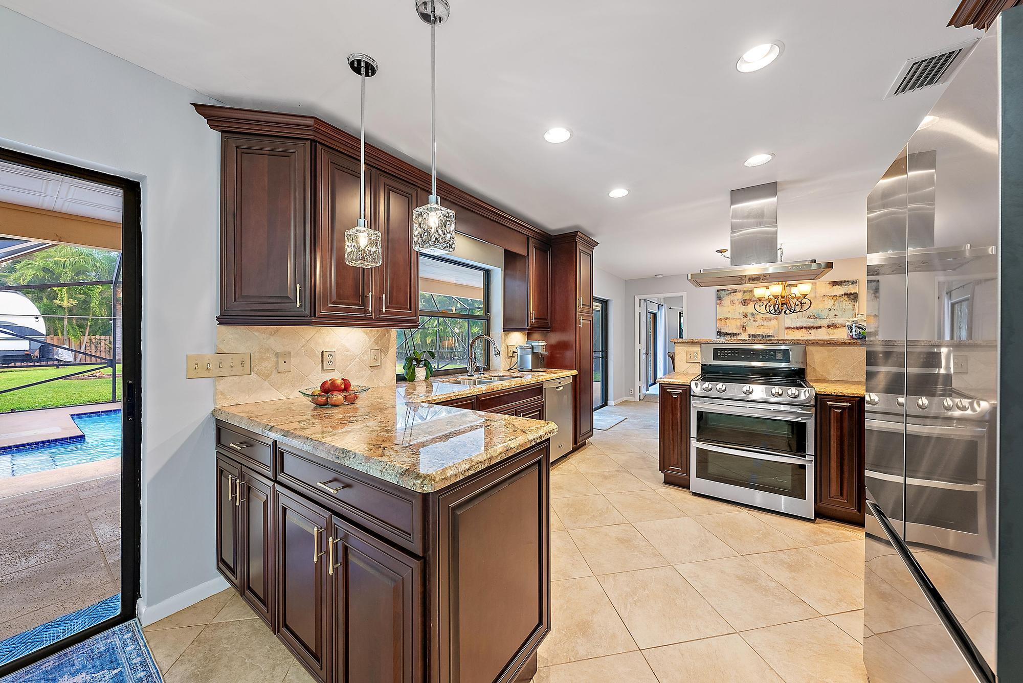 126 Coco Lane Jupiter, FL 33458 - Photo 6 of 40 a kitchen with kitchen island granite countertop a stove oven and a sink with cabinets