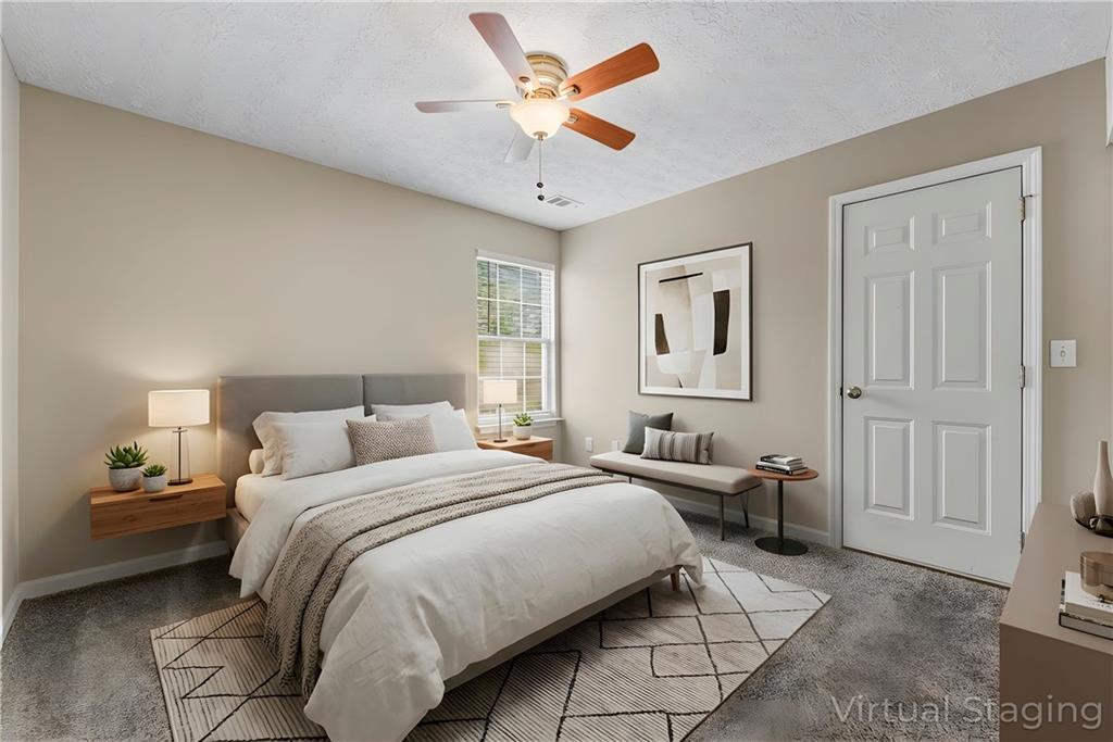 7570 Old Field Cove Road Cumming, GA 30028 - Photo 13 of 18 a bedroom with a large bed and a ceiling fan