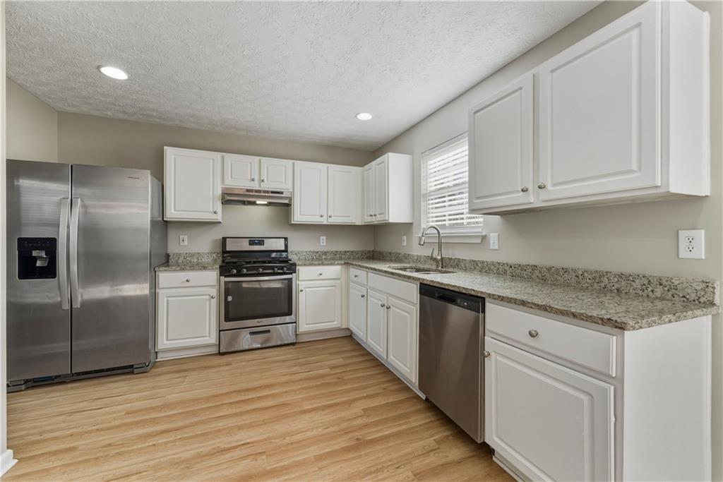 7570 Old Field Cove Road Cumming, GA 30028 - Photo 6 of 18 a kitchen with granite countertop a refrigerator and a sink