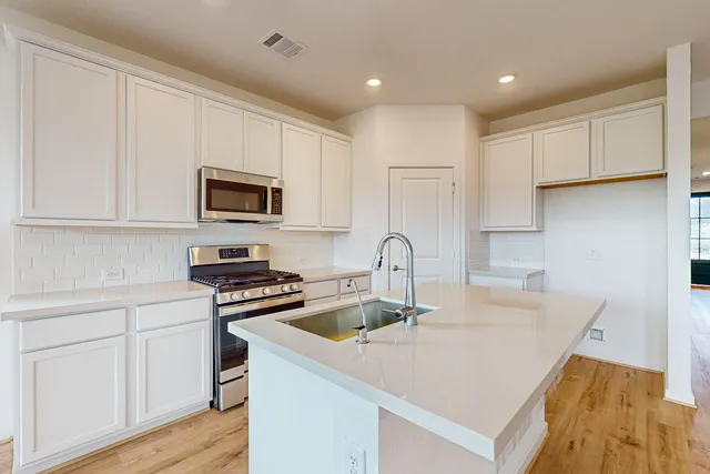 a kitchen with granite countertop a sink a stove and cabinets