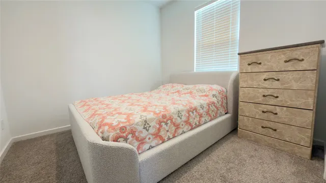 a bed sitting in a bedroom next to a window and dresser