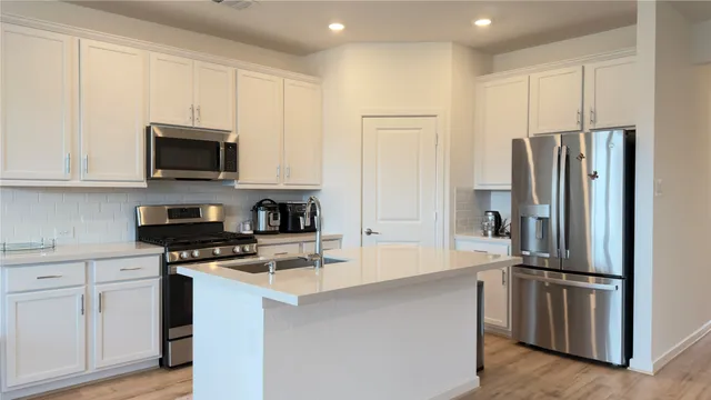 a kitchen with white cabinets and stainless steel appliances