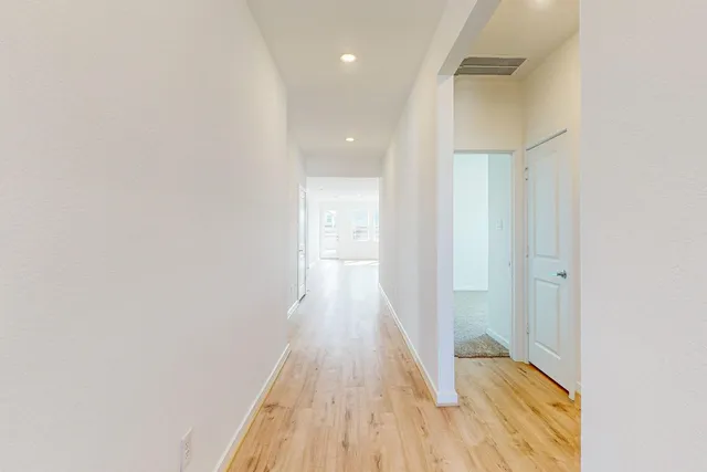 a view of a hallway with wooden floor and a bathroom