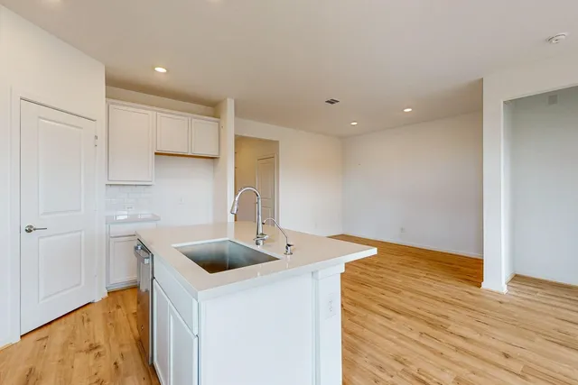 a kitchen with stainless steel appliances a white sink cabinets and wooden floor