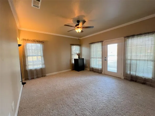 an empty room with chandelier fan and windows