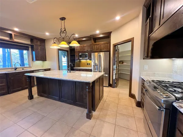 a kitchen with kitchen island granite countertop a stove oven and a refrigerator with cabinets