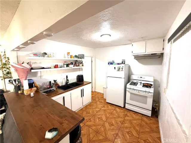 a kitchen with granite countertop a stove a sink and a refrigerator