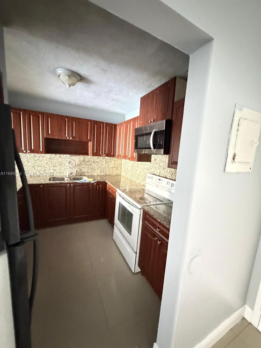 7010 Northwest 186th Street, Unit 5201 Hialeah, FL 33015 - Photo 14 of 29 a kitchen with granite countertop a refrigerator and a stove top oven