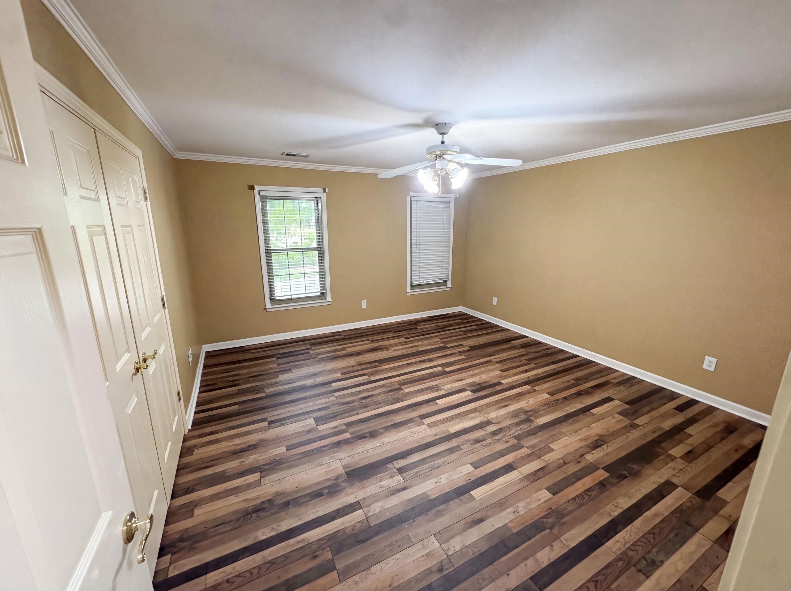 9424 Gotten Road Germantown, TN 38139 - Photo 15 of 27 Spacious room featuring wood-finish flooring, two windows with blinds, a ceiling fan with integrated lighting, and white bi-fold closet doors with brass hardware