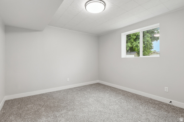 629 King Circle Layton, UT 84041 - Photo 20 of 26 Neutral-toned room featuring a window with exterior foliage, grey carpet flooring, white baseboards, and a flush-mount ceiling light fixture