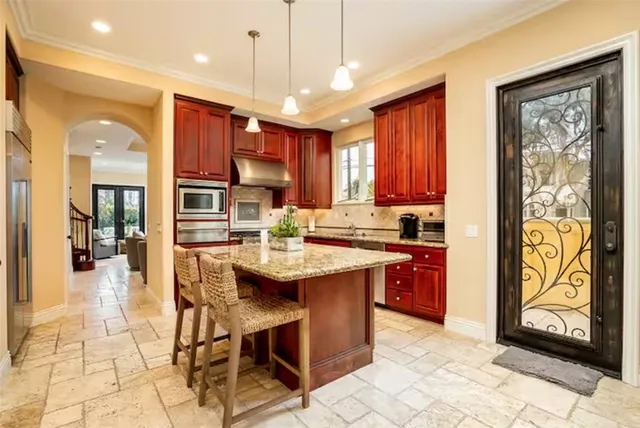 a kitchen with stainless steel appliances granite countertop a sink a stove a kitchen island with chairs and cabinets