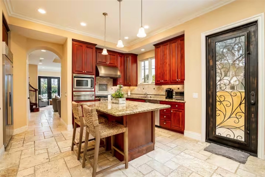 301 16th Street Huntington Beach, CA 92648 - Photo 13 of 16 a kitchen with stainless steel appliances granite countertop a sink a stove a kitchen island with chairs and cabinets