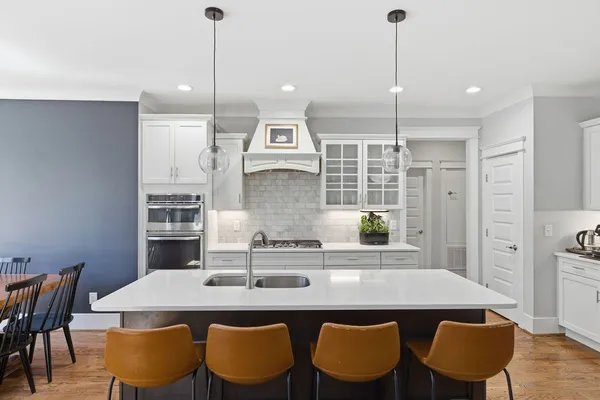 a kitchen with stainless steel appliances granite countertop a dining table chairs and white cabinets