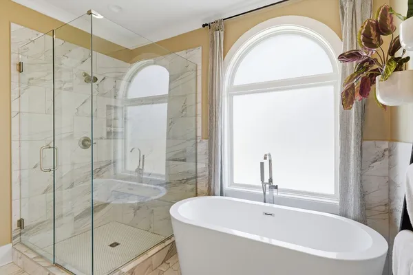 a bathroom with a bathtub a shower a mirror and a sink