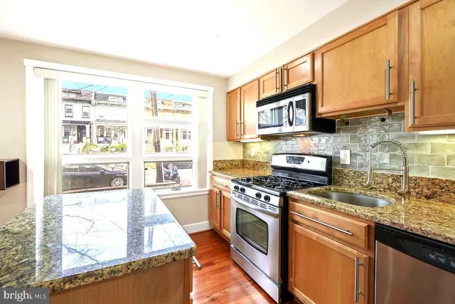 a kitchen with stainless steel appliances granite countertop a stove a sink and a microwave