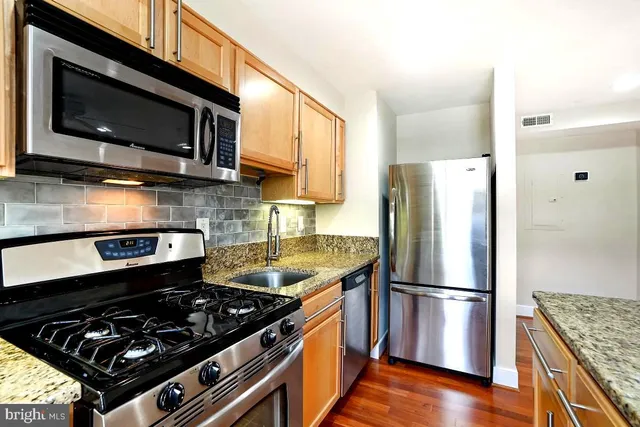 a kitchen with stainless steel appliances granite countertop a stove a refrigerator and a microwave