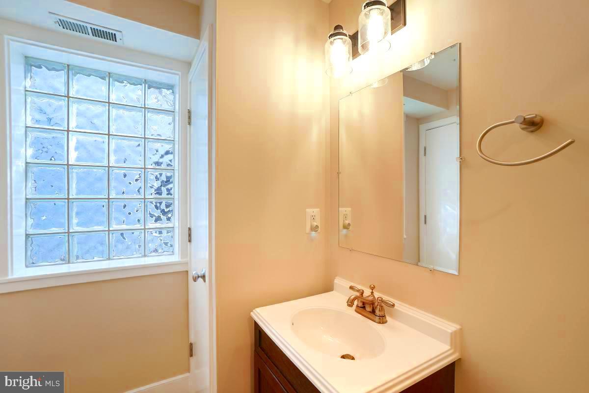 610 Jefferson Street Northwest, Unit 101 Washington, DC 20011 - Photo 20 of 24 a bathroom with a sink a mirror a vanity and a shower