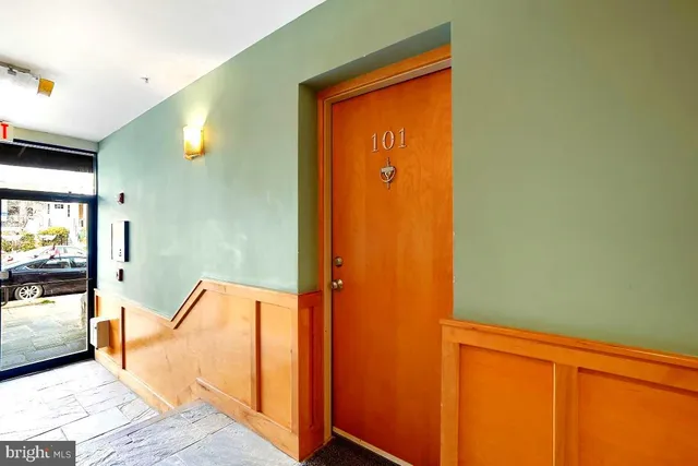a view of a hallway with wooden floor and a bathroom