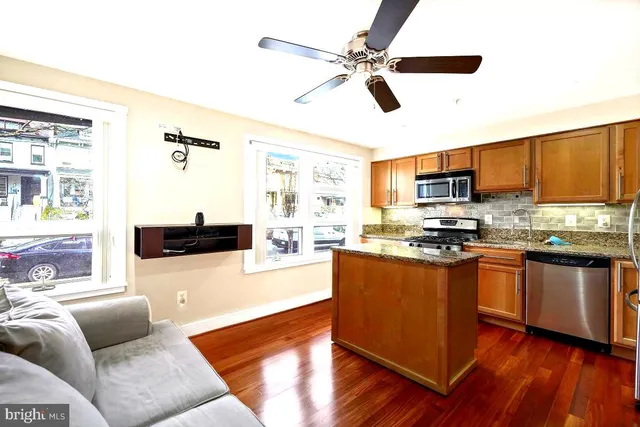 a kitchen with stainless steel appliances granite countertop a refrigerator a stove top oven a sink with island and chairs