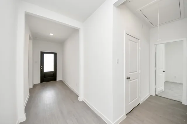a view of a hallway with wooden floor and a bathroom