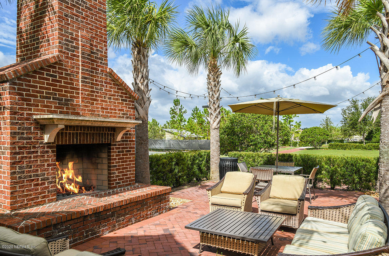 322 Footbridge Road St. Johns, FL 32259 - Photo 17 of 25 a view of a patio with a table and chairs under an umbrella with a fire pit and potted plants