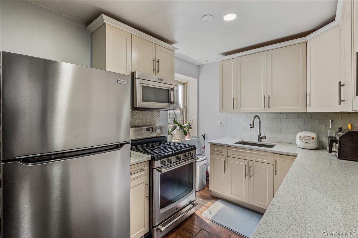 144-55 Melbourne Avenue, Unit 6E Queens, NY 11367 - Photo 17 of 24 Kitchen with stainless steel appliances, light stone counters, decorative backsplash, dark wood-style floors, and recessed lighting