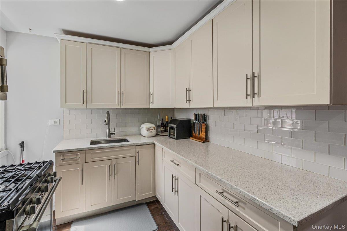 144-55 Melbourne Avenue, Unit 6E Queens, NY 11367 - Photo 19 of 24 Kitchen featuring light stone countertops, gas stove, and backsplash