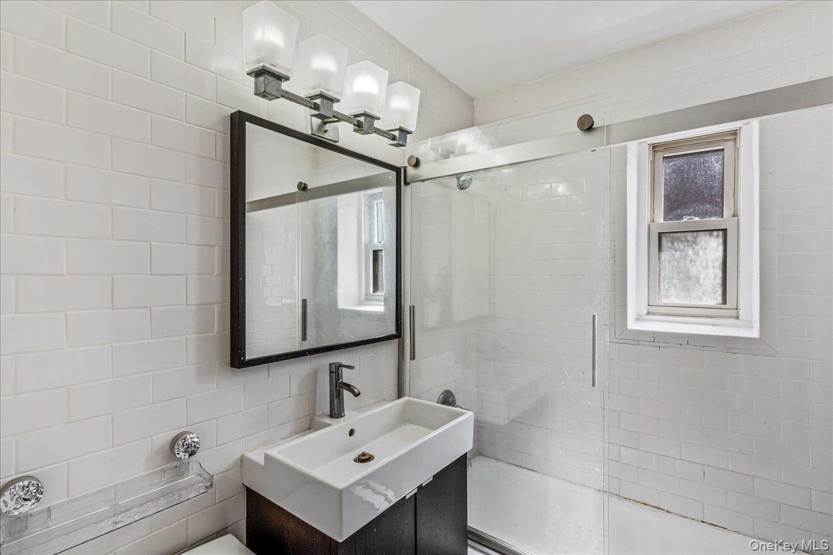 144-55 Melbourne Avenue, Unit 6E Queens, NY 11367 - Photo 21 of 24 Full bathroom with shower / bath combination with glass door, vanity, and tile walls