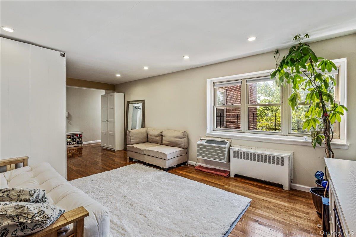 144-55 Melbourne Avenue, Unit 6E Queens, NY 11367 - Photo 8 of 24 Living room featuring radiator, dark wood-type flooring, recessed lighting, and an AC wall unit