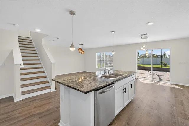 a view of an empty room with kitchen and window