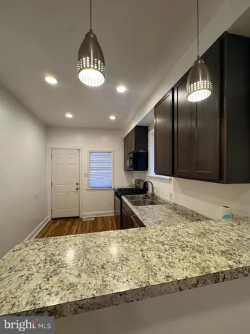 a view of a kitchen with kitchen island granite countertop living room and stainless steel appliances