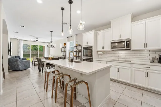 a kitchen with stainless steel appliances a stove a sink a microwave a center island and furniture