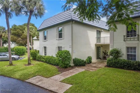 a view of a house with a yard plants and palm trees