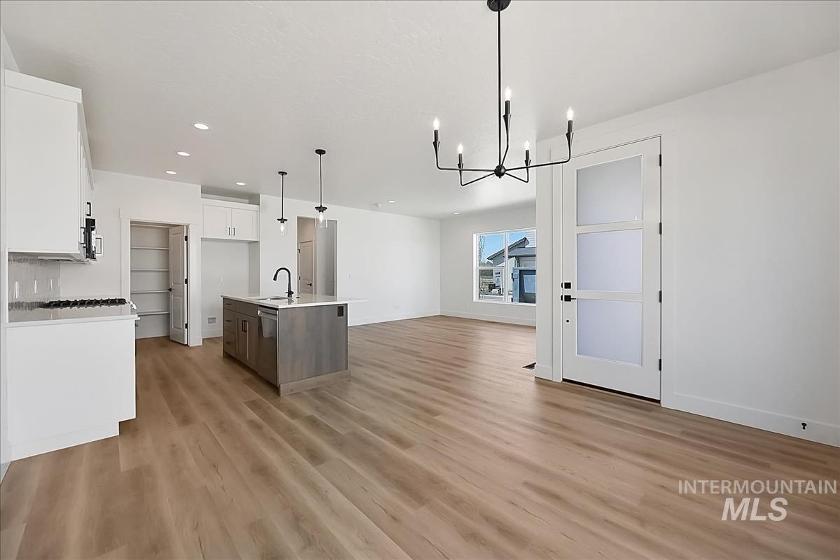 776 South Calhoun Lane Star, ID 83669 - Photo 14 of 49 Open-concept living area featuring wood-finish flooring, a modern kitchen island with seating, white shaker-style cabinetry, recessed lighting, and a contemporary entry door with frosted panels