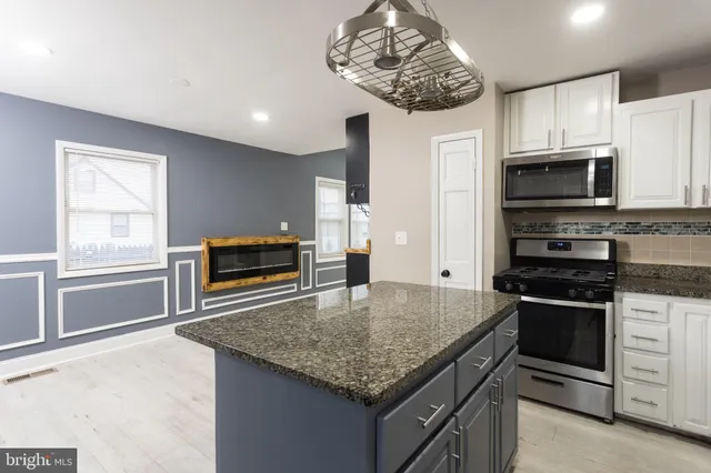 a kitchen with stainless steel appliances granite countertop a kitchen island a stove and a sink