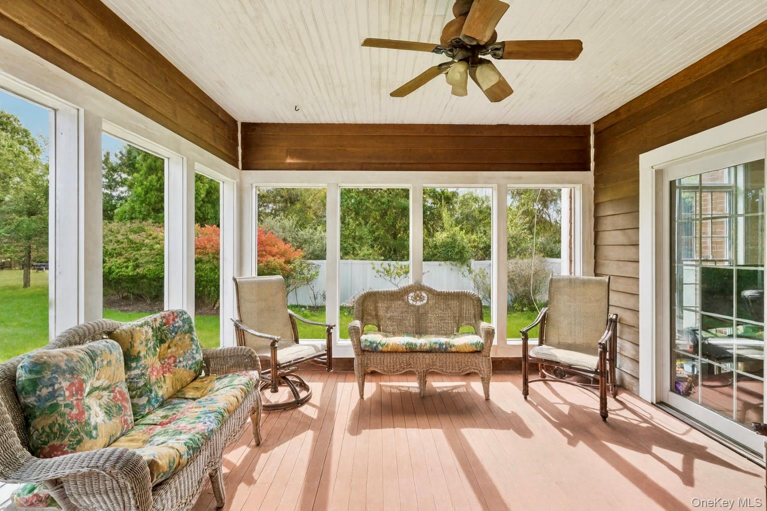 12 Laila Lane Remsenburg, NY 11960 - Photo 8 of 50 Sunroom featuring a ceiling fan, mahogany wood walls, and a warm, inviting ambiance.