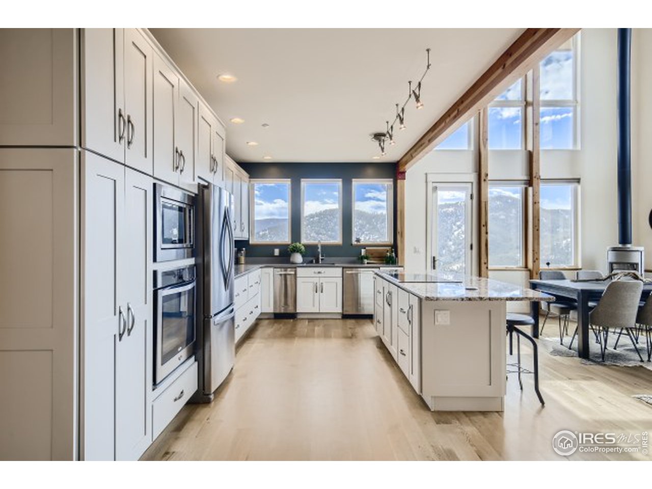 1133 Arroyo Chico Road Boulder, CO 80302 - Photo 12 of 37 a open kitchen with stainless steel appliances kitchen island granite countertop a refrigerator a sink dishwasher a dining table and chairs with wooden floor