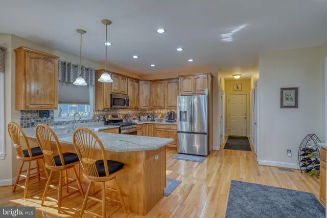 a kitchen with granite countertop a table chairs microwave and refrigerator