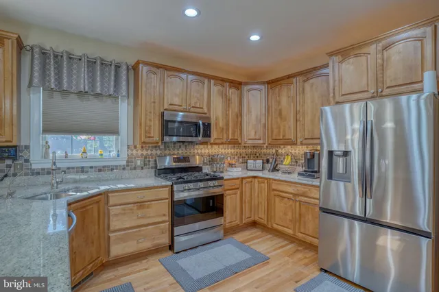 a kitchen with stainless steel appliances granite countertop a stove top oven a sink dishwasher a dining table and chairs with wooden floor