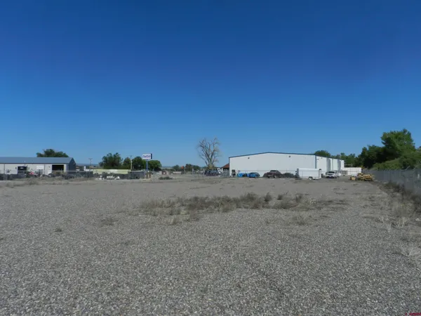 a view of a dry field with trees in the background
