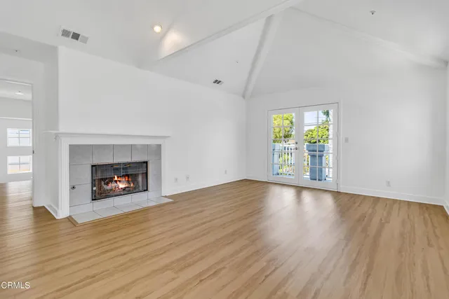 an empty room with wooden floor a fireplace and a window