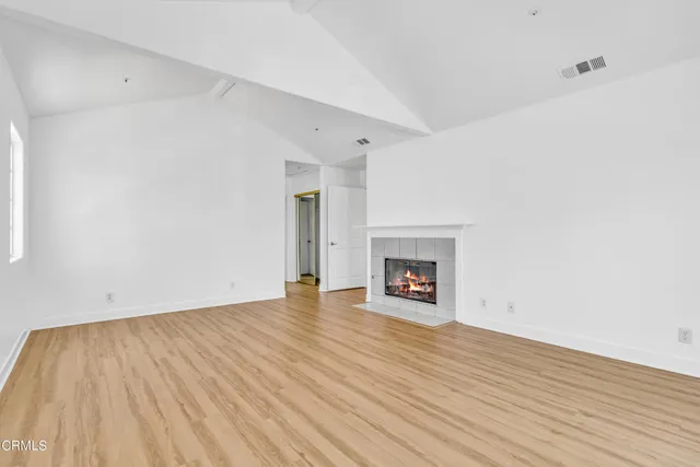 an empty room with wooden floor and a fireplace