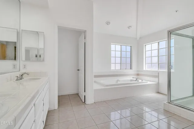 a spacious bathroom with a tub sink and mirror
