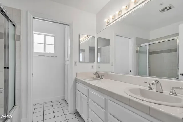 a bathroom with a double vanity sink mirror and next to a window