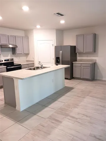 a kitchen with a sink a stove a refrigerator and cabinets